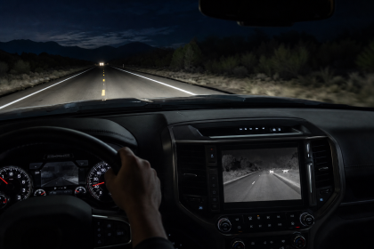 Dashboard display and rearview camera view on a dark road at night