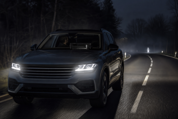 Automotive thermal night vision display highlighting a pedestrian on a dark road